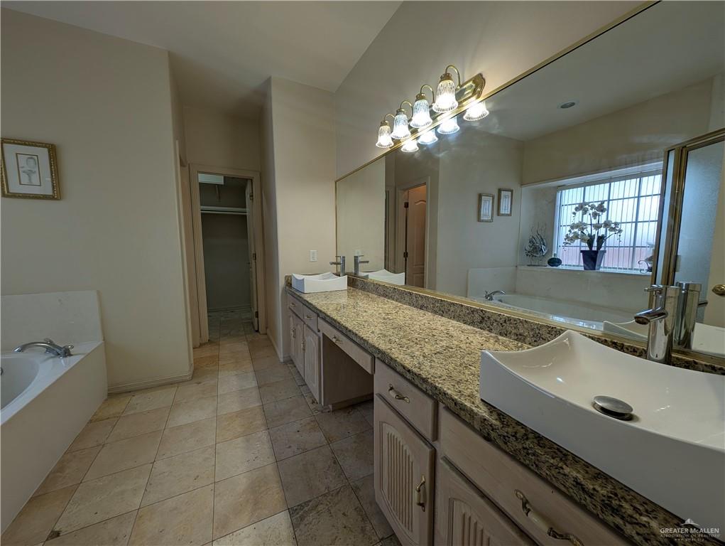 2000 East 25th Street Mission, TX 78574 - Photo 15 of 27 Bathroom with a garden tub, double vanity, a spacious closet, and light tile patterned floors