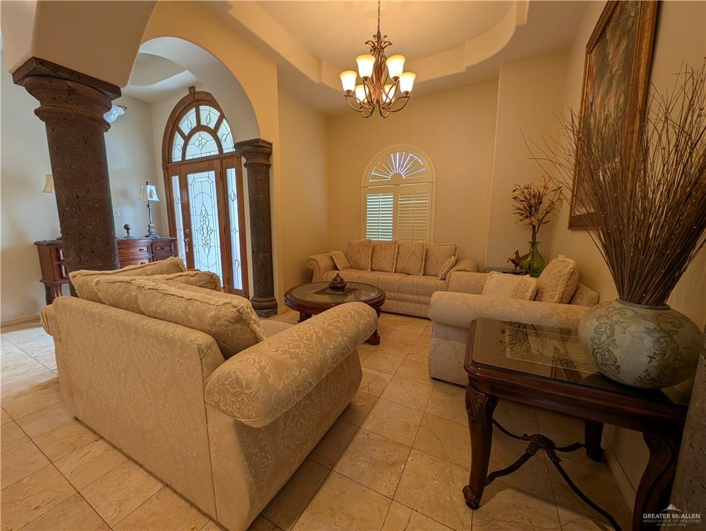2000 East 25th Street Mission, TX 78574 - Photo 5 of 27 Living room with arched walkways, a raised ceiling, a towering ceiling, light tile patterned floors, and a chandelier