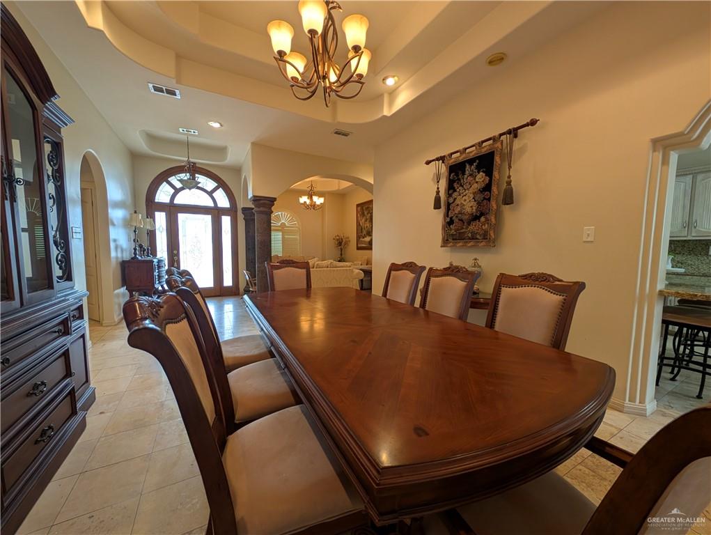 2000 East 25th Street Mission, TX 78574 - Photo 6 of 27 Dining area featuring arched walkways, a tray ceiling, a chandelier, and light tile patterned floors
