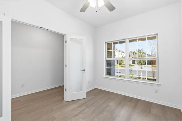 a view of an empty room with wooden floor and a window
