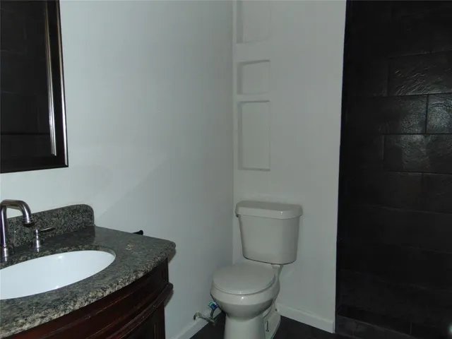 a bathroom with a granite countertop toilet and a sink