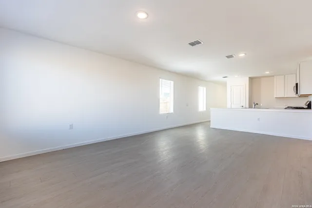 a view of an empty room with a window and wooden floor