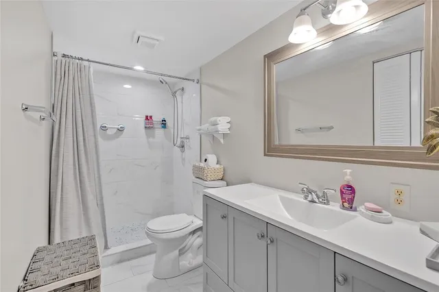 a bathroom with a granite countertop sink a toilet a shower and a mirror