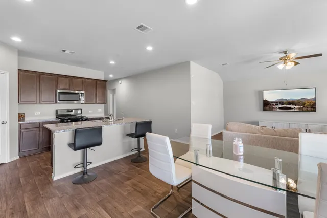 a kitchen with kitchen island a stove a sink a dining table and chairs