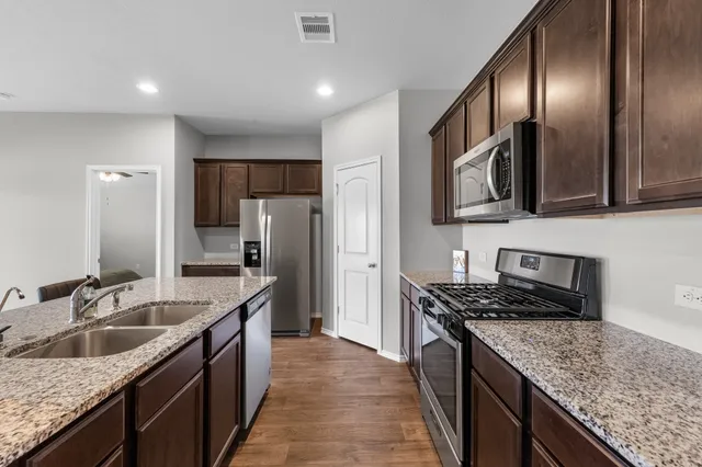 a kitchen with stainless steel appliances granite countertop a sink stove and refrigerator