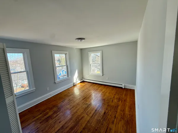 a view of an empty room with wooden floor and a window