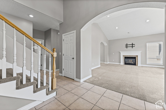 14038 New Saddle Road Draper, UT 84020 - Photo 2 of 46 Tile flooring, carpeted stairs with wood railing, vaulted ceiling, arched doorway, and a fireplace with mantle