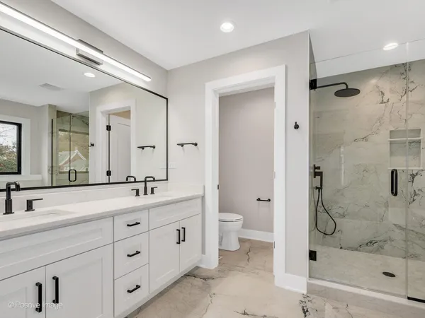 a bathroom with a double vanity sink toilet mirror and shower