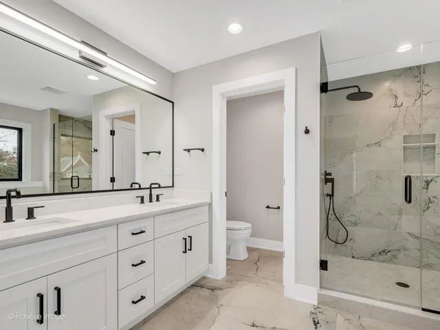 a bathroom with a double vanity sink toilet mirror and shower