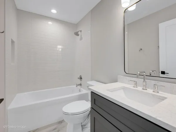 a bathroom with a granite countertop sink a toilet and bathtub