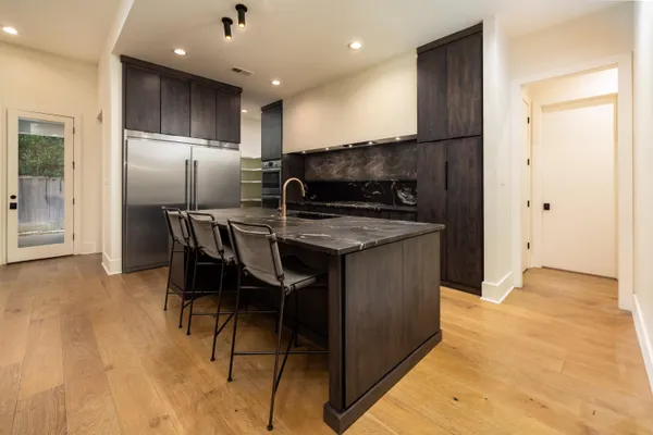 a kitchen with stainless steel appliances granite countertop a table chairs a refrigerator and a sink