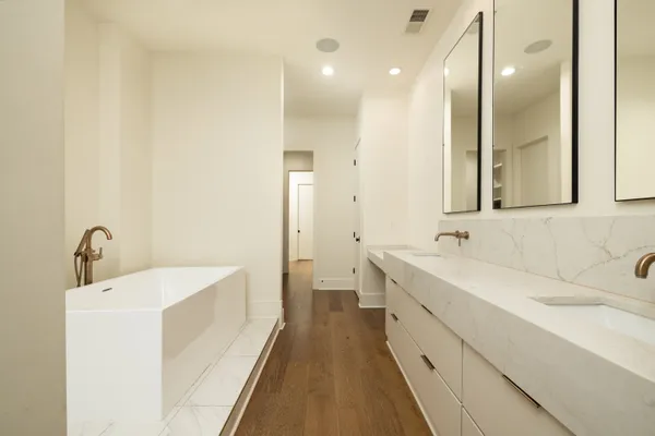 a bathroom with a double vanity sink and mirror with bathtub