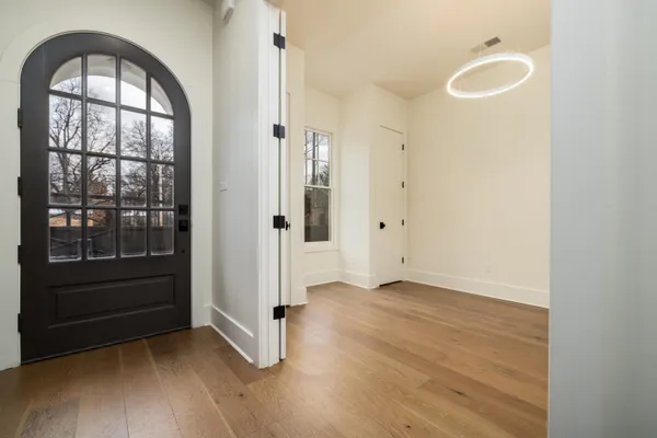 an empty room with wooden floor cabinet and windows