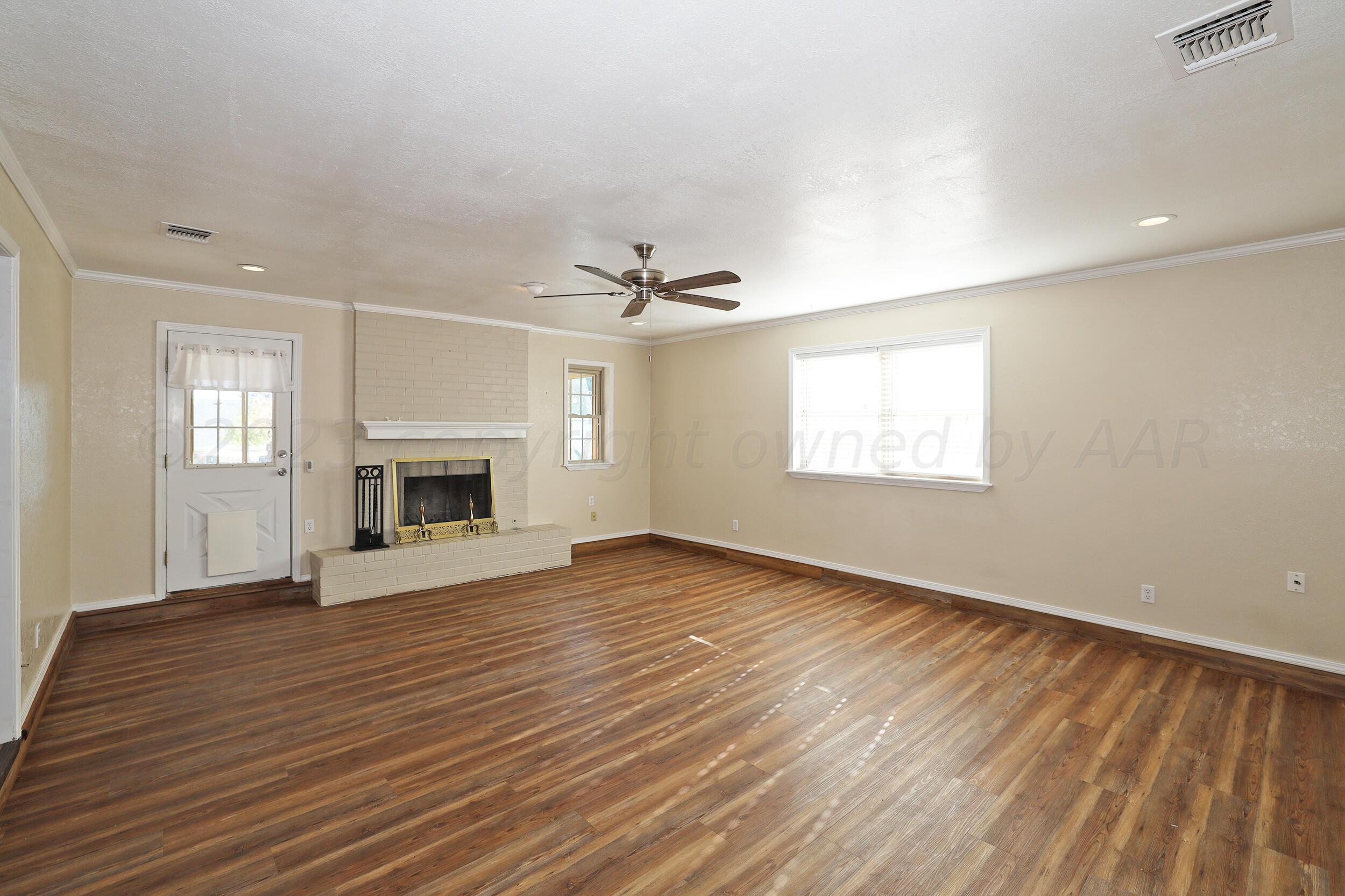 2905 Salem Drive Amarillo, TX 79110 - Photo 10 of 29 an empty room with wooden floor fireplace and windows