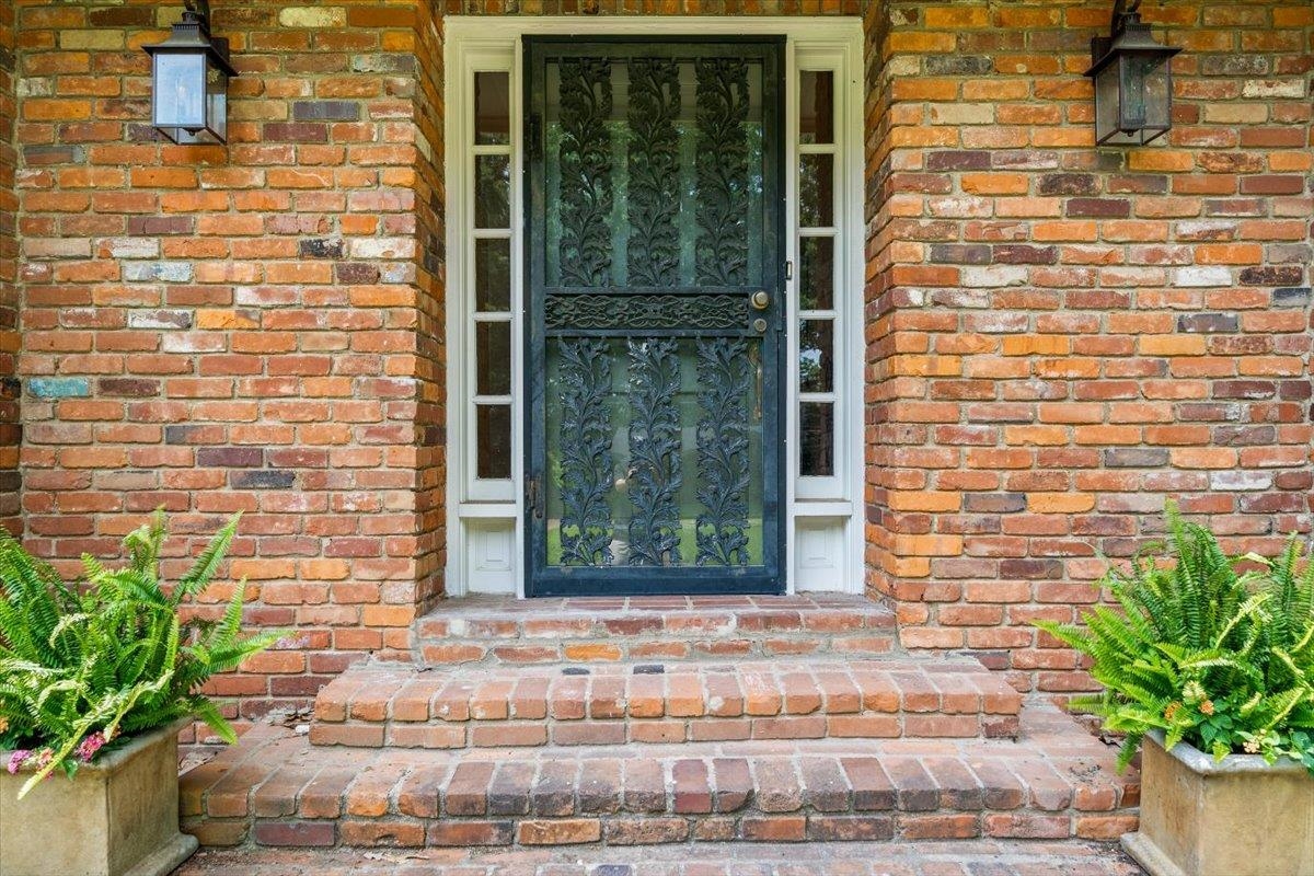 1273 Brookfield Road Memphis, TN 38119 - Photo 4 of 40 Brick facade entryway featuring an ornate black security screen door, sidelight windows, and matching exterior sconces