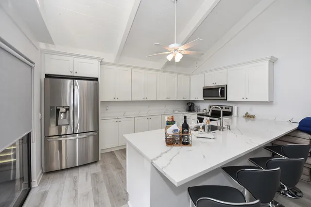 a kitchen with stainless steel appliances a sink a stove a refrigerator cabinets and a dining table