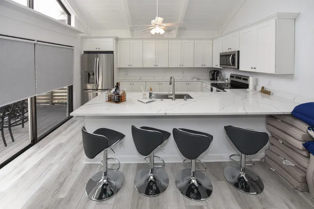 a kitchen with stainless steel appliances granite countertop a sink a stove a refrigerator and chairs