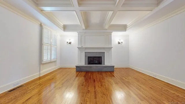 a view of an empty room with wooden floor fireplace and a window