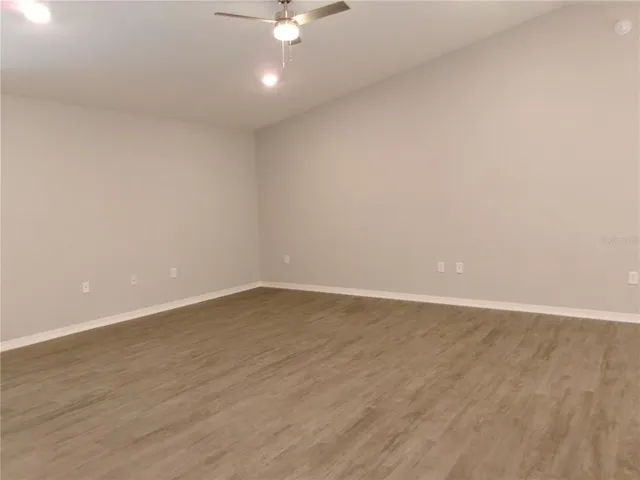 an empty room with wooden floor and fan