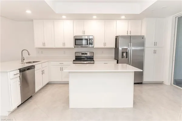 a kitchen with stainless steel appliances a refrigerator sink and white cabinets