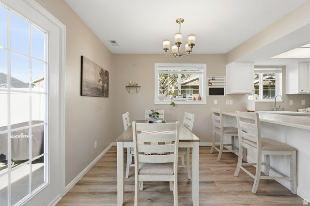 99 Penhurst Place Logan, UT 84341 - Photo 10 of 34 Open-concept dining area featuring wood-finish flooring, a contemporary chandelier, and direct access to the exterior through a glass-paned door