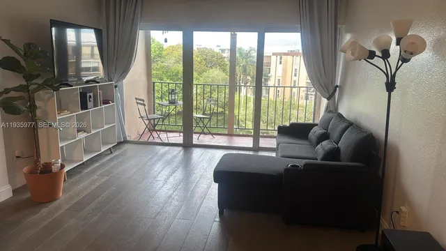 a living room with furniture large window and wooden floor