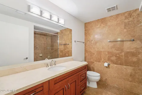 a bathroom with a granite countertop sink a toilet a mirror and shower