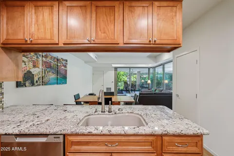 a view of kitchen with granite countertop stainless steel appliances sink and cabinets