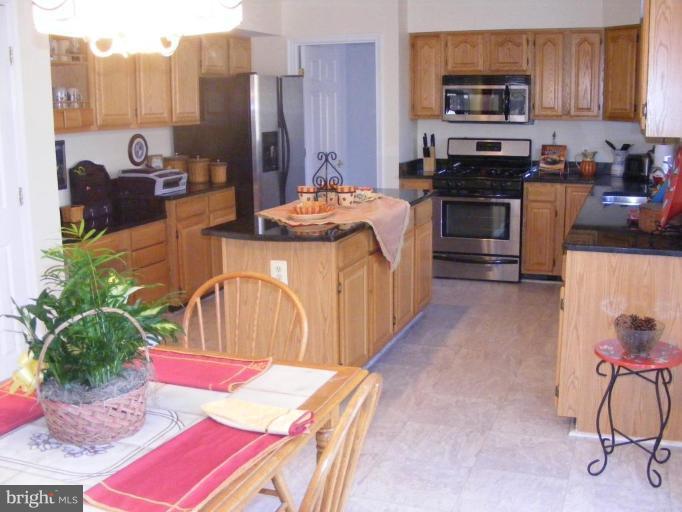 1219 Providence Road Towson, MD 21286 - Photo 23 of 27 a kitchen with stainless steel appliances kitchen island granite countertop a refrigerator a stove a sink dishwasher with a dining table and chairs