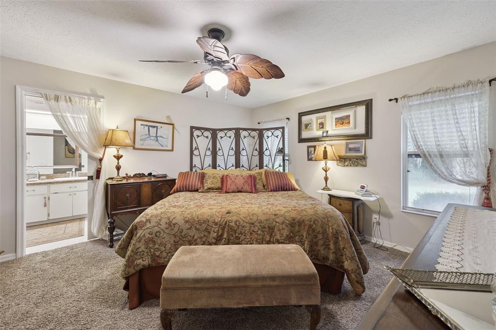 26600 Racquet Circle Leesburg, FL 34748 - Photo 29 of 80 a spacious bedroom with a bed a table and chair