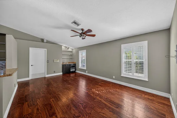 a view of an empty room with a window and wooden floor