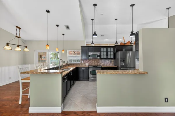 a kitchen with stainless steel appliances granite countertop a sink a stove and a wooden floors