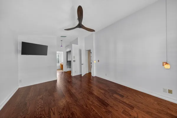 a view of empty room with wooden floor and fan