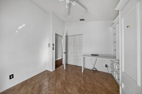 a view of empty room with wooden floor and ceiling fan