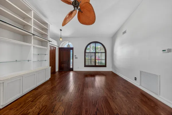 a view of empty room with wooden floor and fan