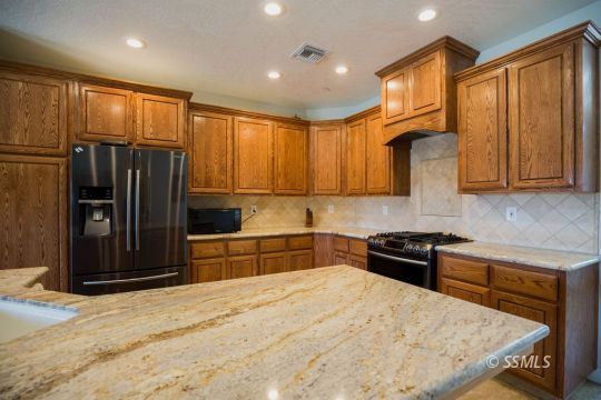 2401 Lacey Street Ridgecrest, CA 93555 - Photo 11 of 44 a kitchen with stainless steel appliances granite countertop a refrigerator stove top oven and sink