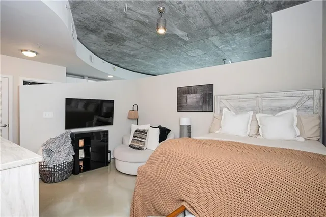 a bedroom with a bed a television and a large window