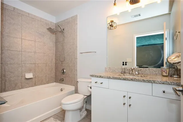 a bathroom with a granite countertop sink toilet mirror vanity and bathtub