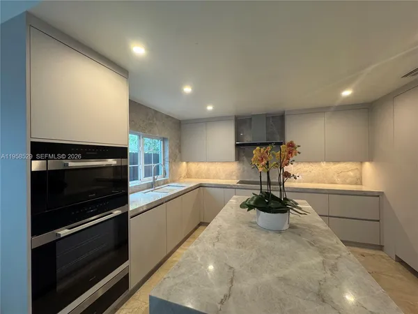 a kitchen with kitchen island granite countertop a stove and a wooden floors