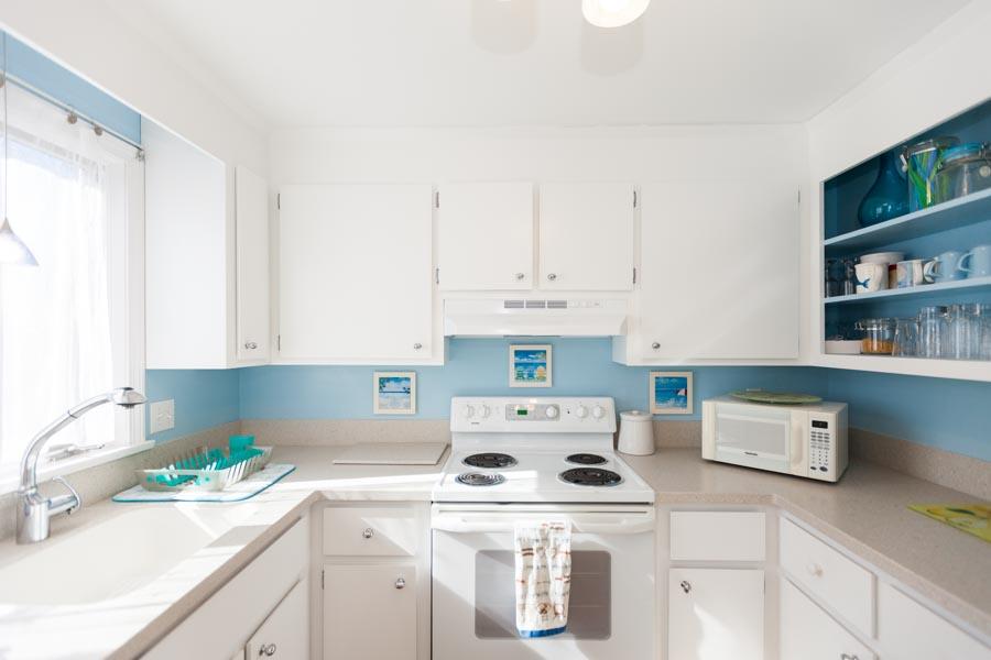 99 Depot Road, Unit 24 Chatham, MA 02633 - Photo 6 of 17 a kitchen with a white stove top oven and white cabinets with wooden floor