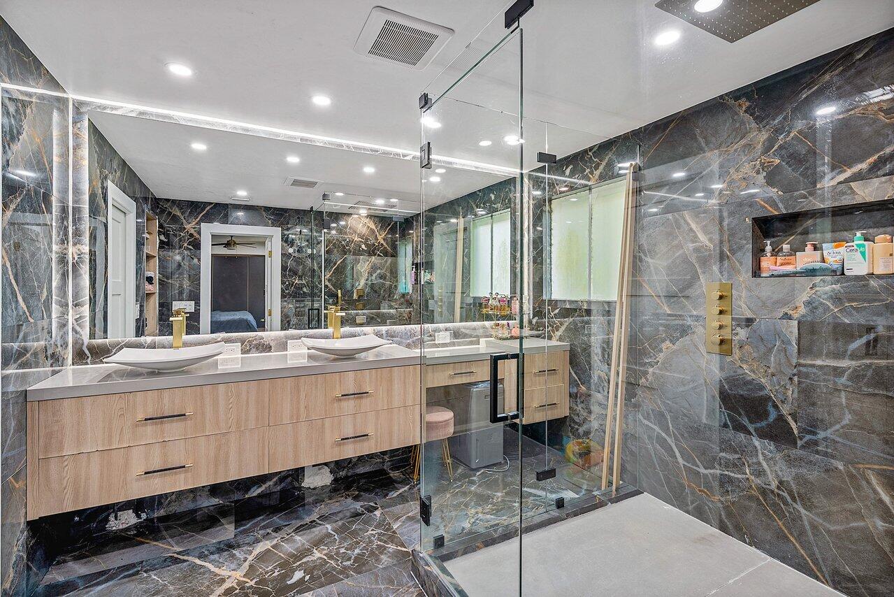 10223 Boca Vista Drive Boca Raton, FL 33498 - Photo 18 of 33 a large bathroom with a large mirror vanity and a sink