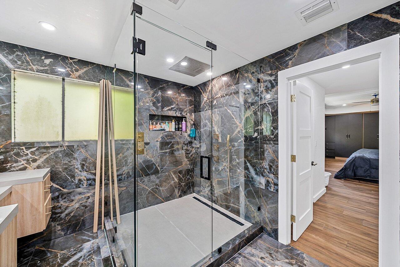 10223 Boca Vista Drive Boca Raton, FL 33498 - Photo 19 of 33 a bathroom with a glass shower door and a bathtub