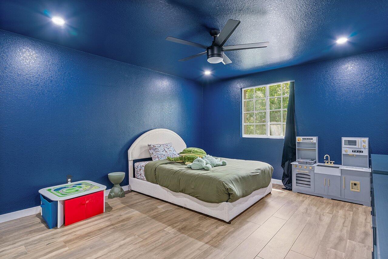 10223 Boca Vista Drive Boca Raton, FL 33498 - Photo 21 of 33 a living room with a bed and a chandelier