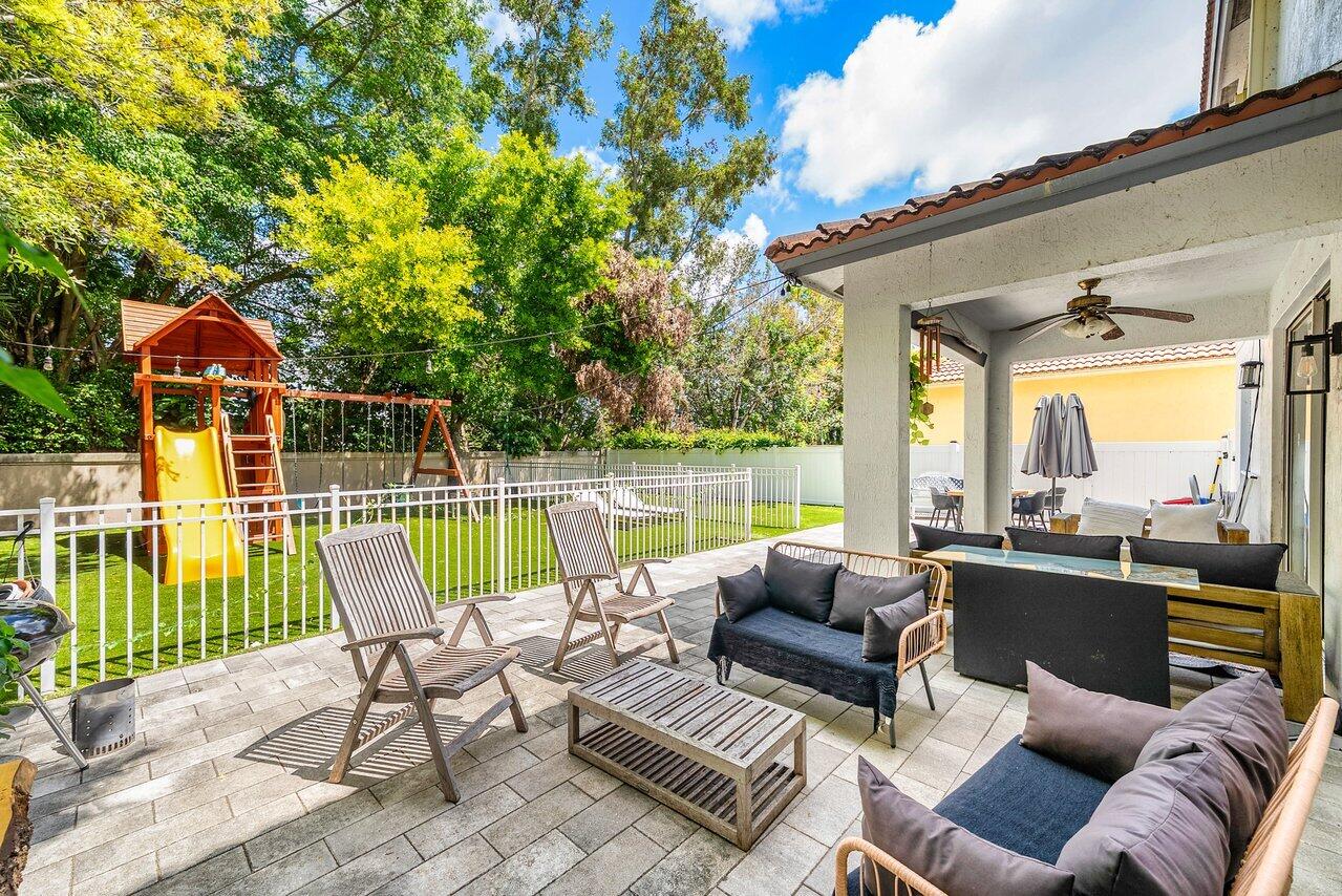 10223 Boca Vista Drive Boca Raton, FL 33498 - Photo 29 of 33 a view of a patio with couches chairs and a floor to ceiling window next to a yard
