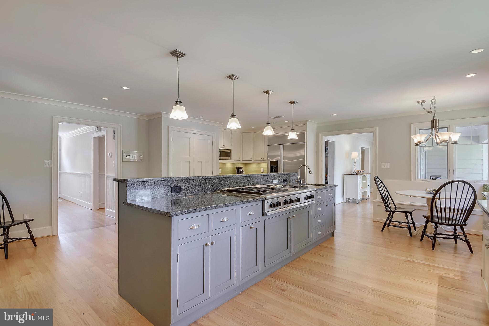 12408 Beall Spring Road Potomac, MD 20854 - Photo 6 of 30 a large kitchen with granite countertop a stove top oven a sink a dining table and chairs with wooden floor