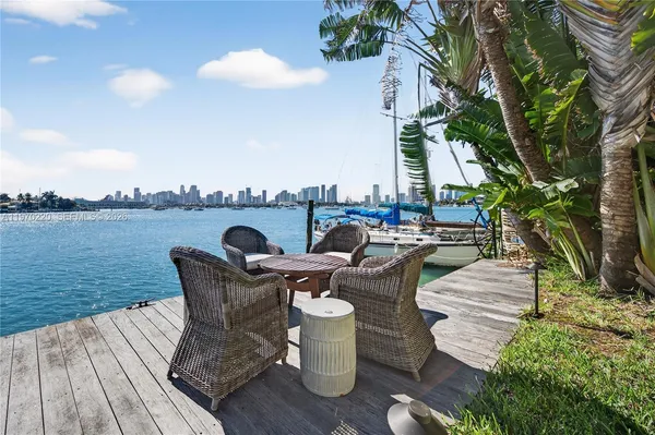 a view of a patio with couches table and chairs and potted plants with wooden floor and fence