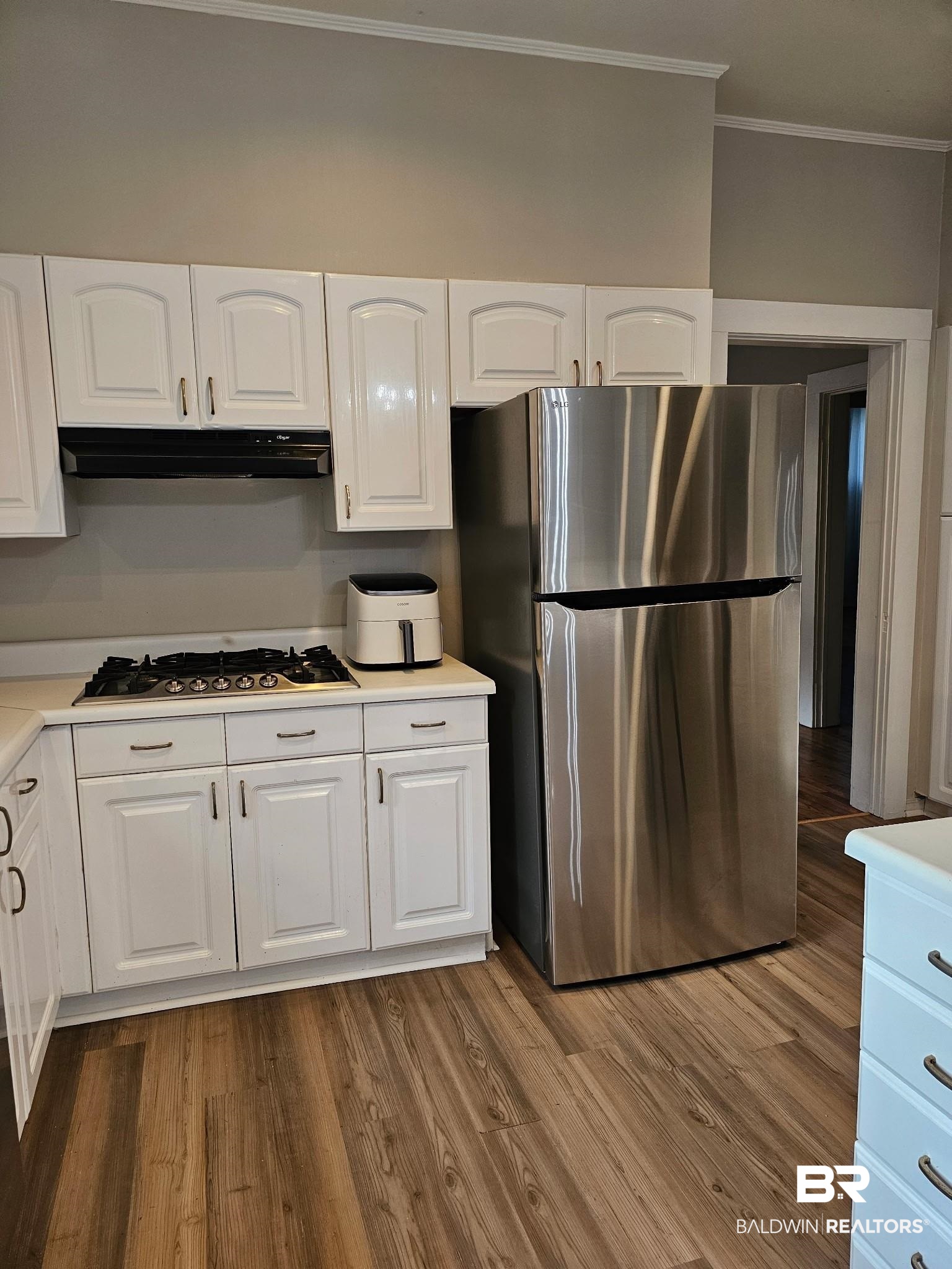 1215 Church Street Mobile, AL 36604 - Photo 10 of 23 Kitchen with white cabinets, wood finished floors, under cabinet range hood, and appliances with stainless steel finishes
