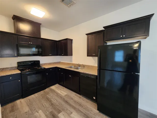 a kitchen with granite countertop a refrigerator and a stove top oven