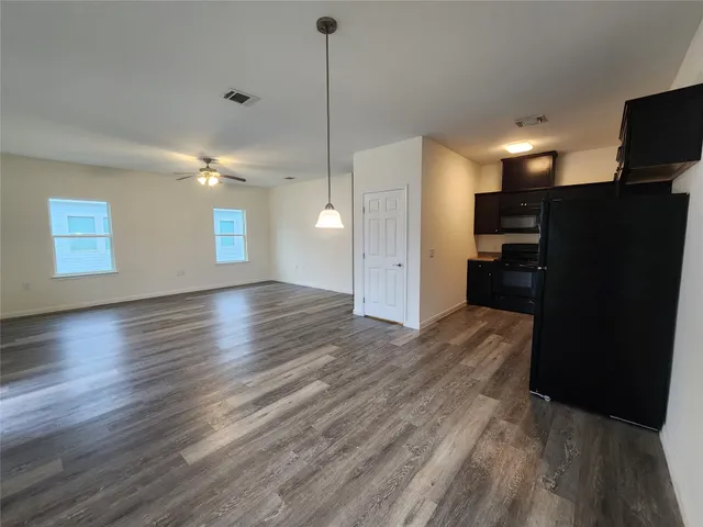 a view of a kitchen with a refrigerator and wooden floor
