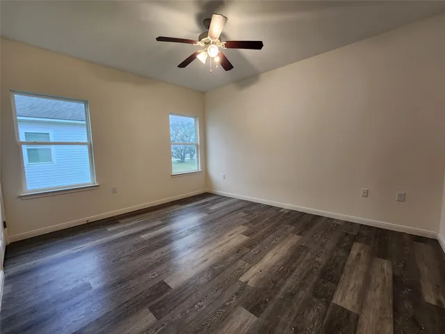 a view of empty room with wooden floor and fan